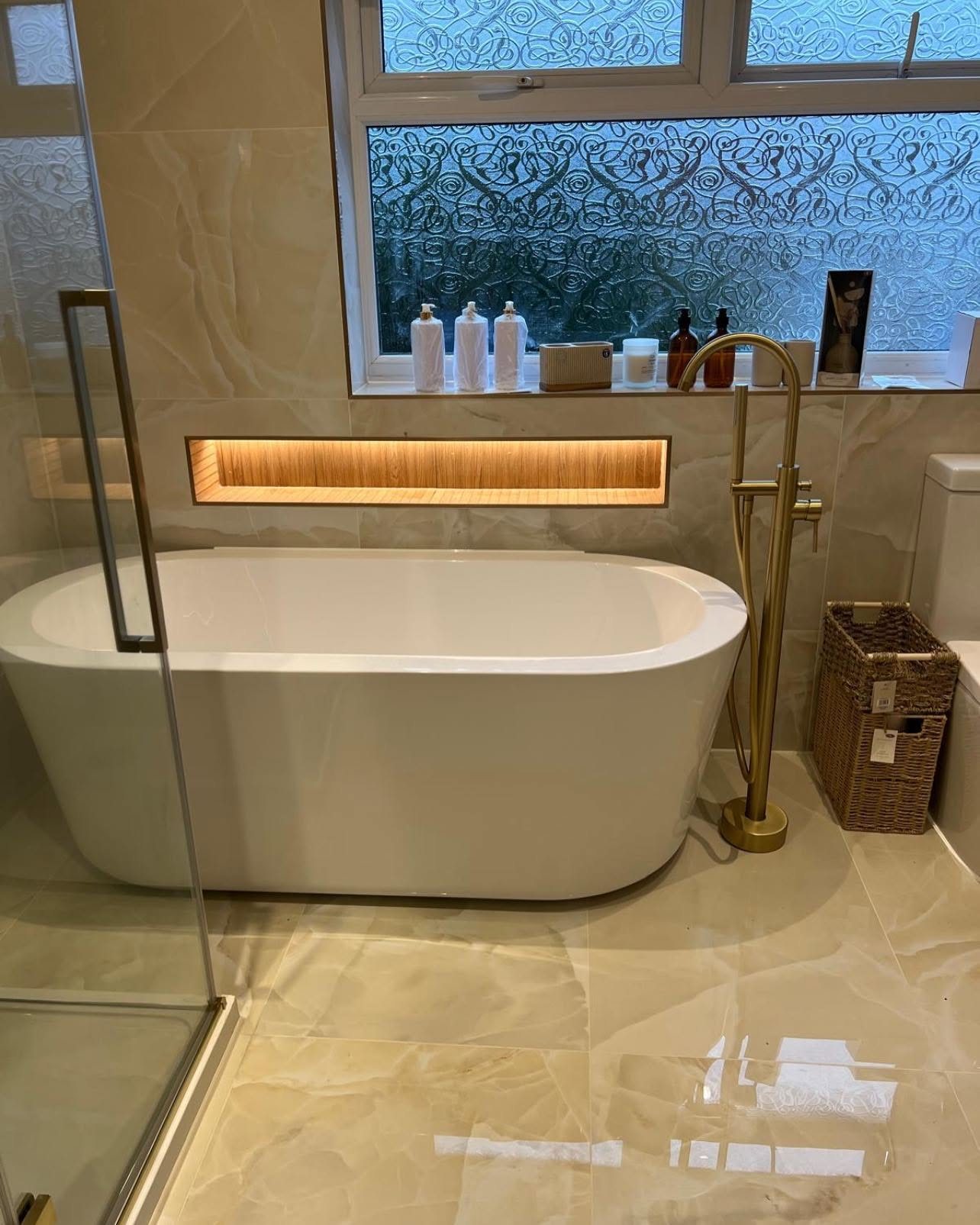 Freestanding bath with brushed gold fittings by Nevill Construction Ltd