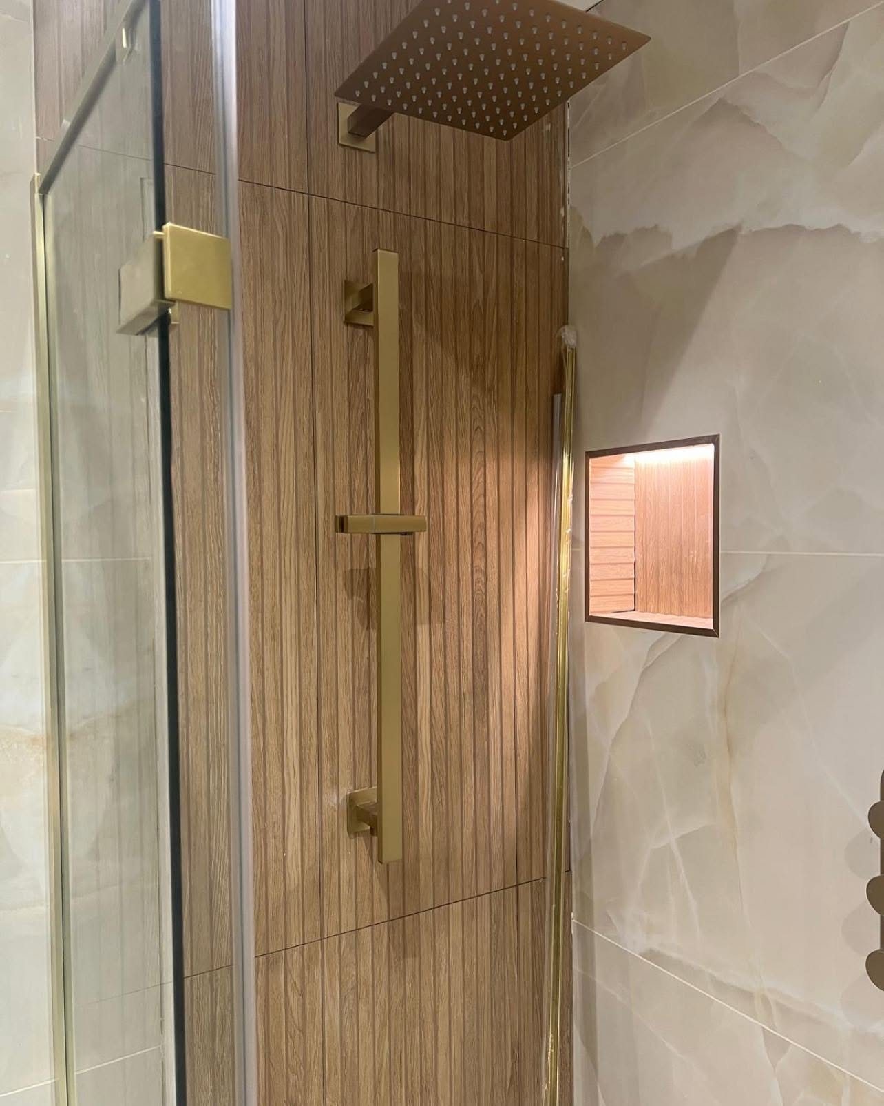 Walk-in shower with brushed gold fittings and wood-effect tiling