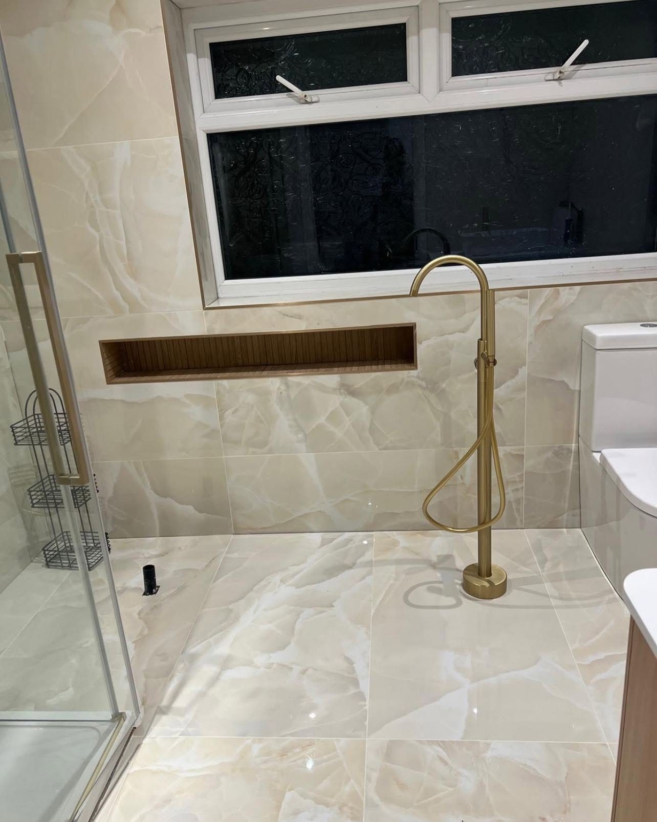 Onyx-effect tiling with freestanding gold bath tap